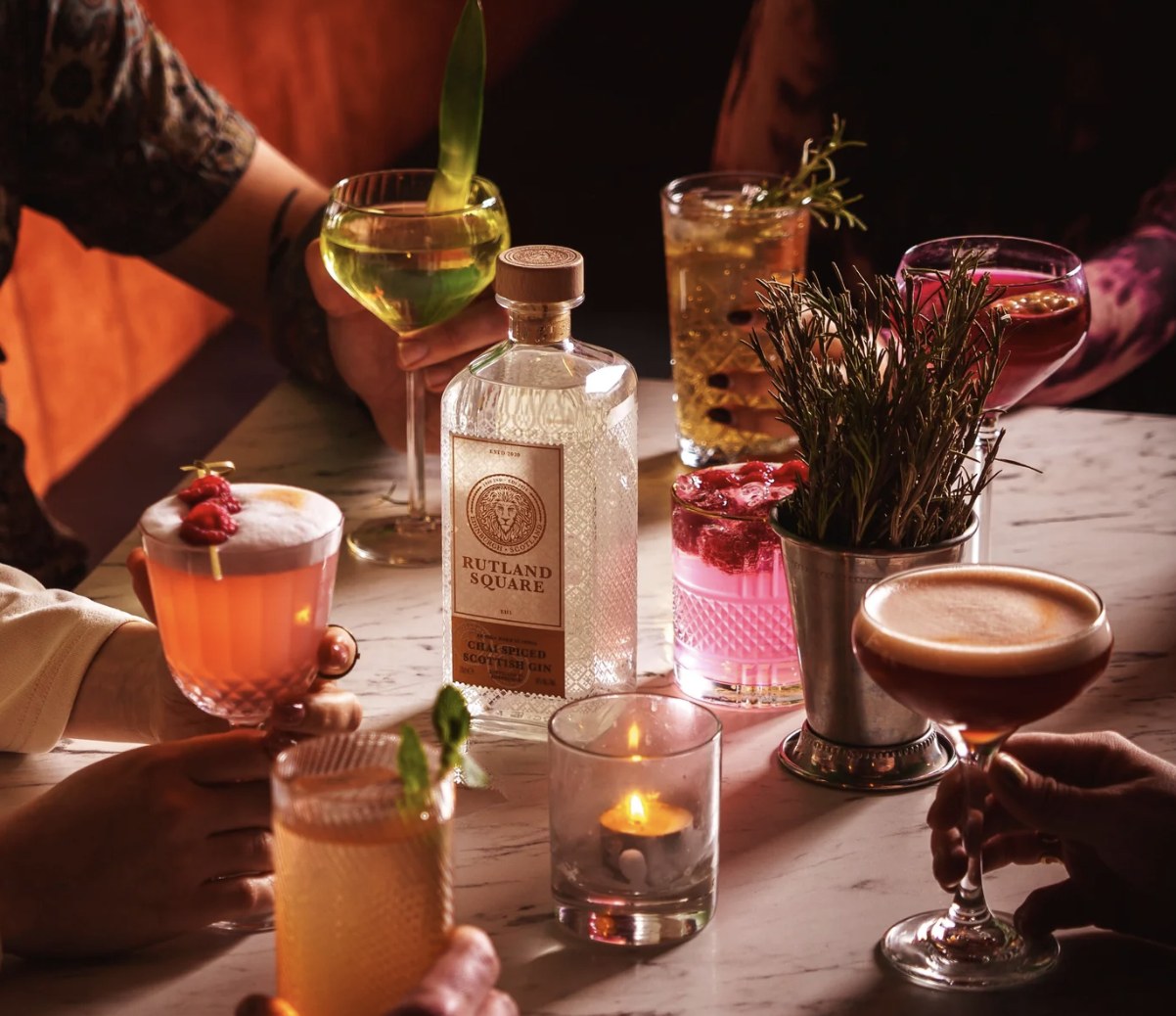 Rutland Square Chai Spiced Scottish Gin surrounded by cocktails by candlelight
